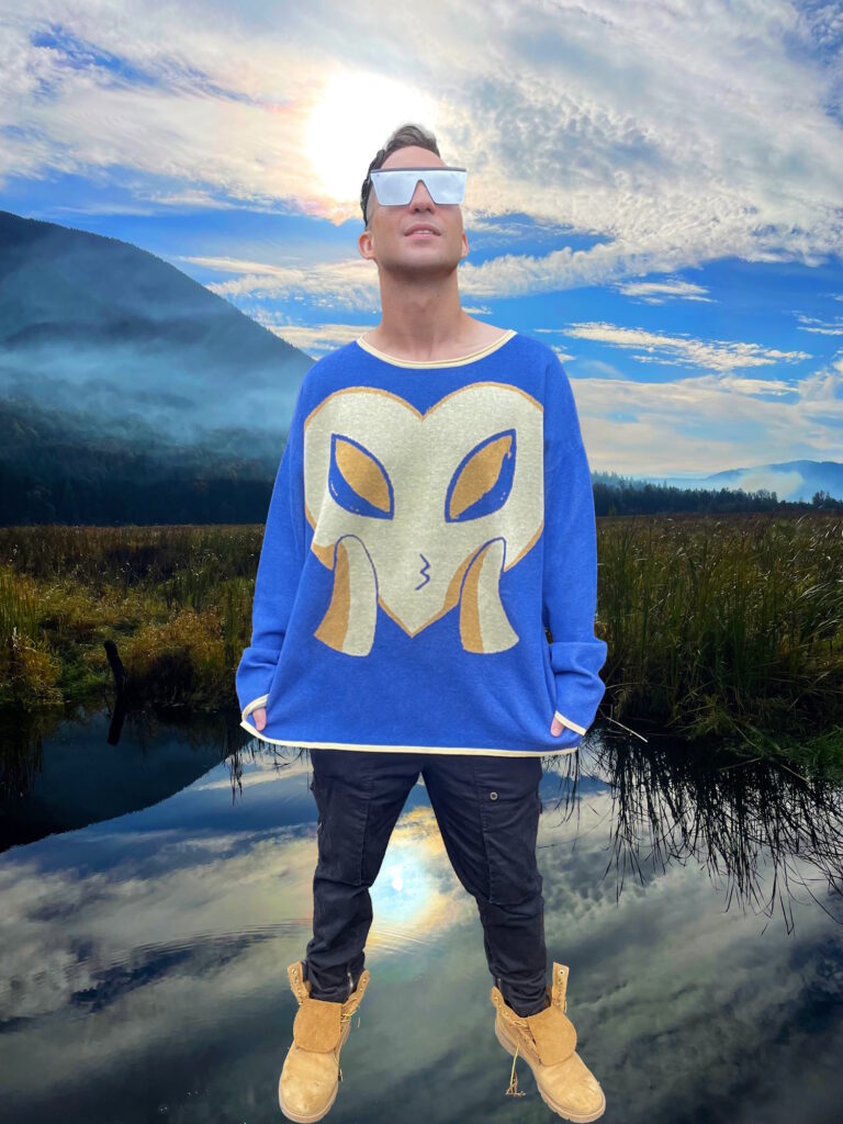 Male model looks up to the sky wearing blue and yellow sweater. A yellow heart and a blue background. The yellow heart has alien eyes and blows the viewer a kiss.