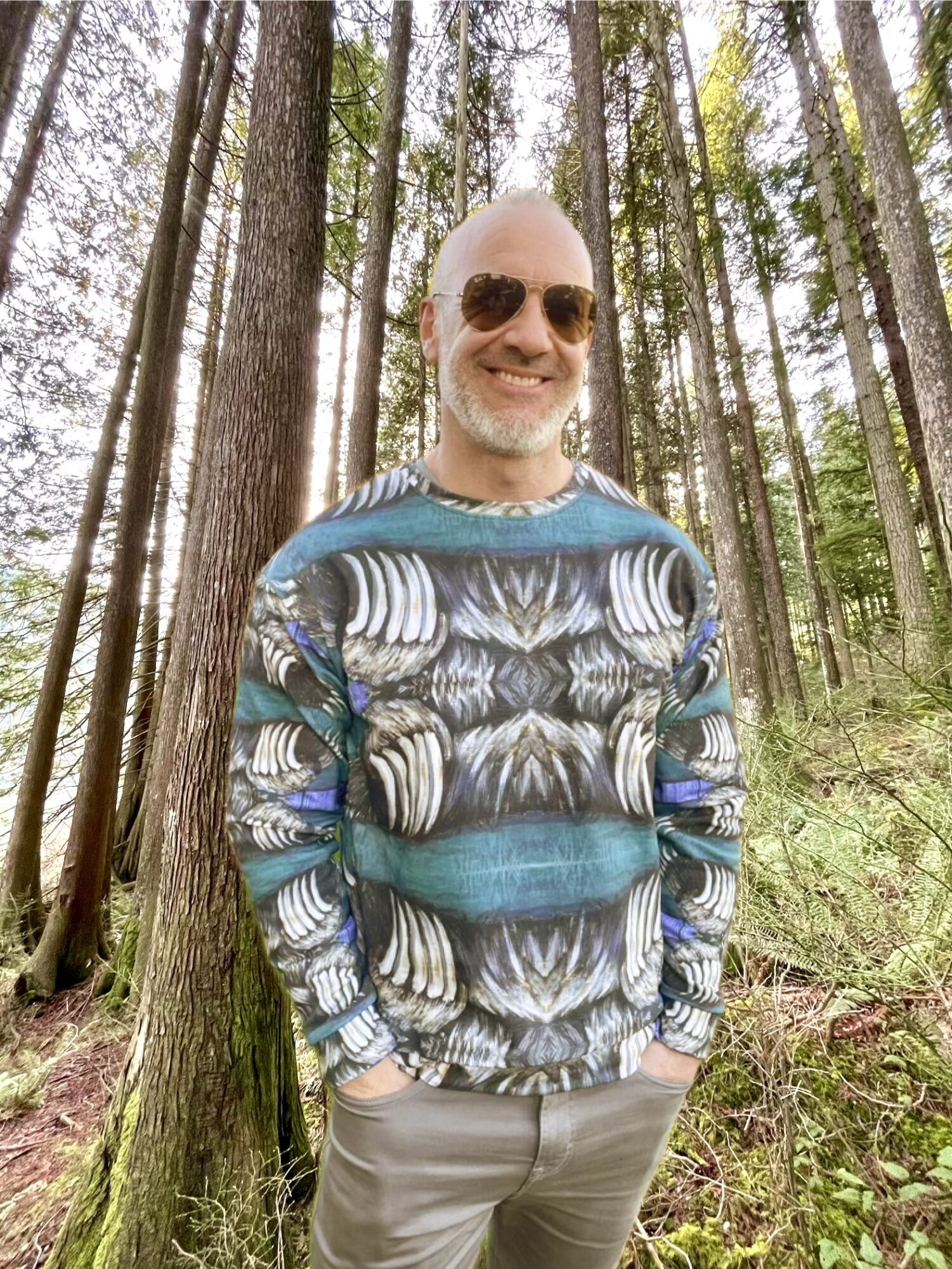 Model in the Bear Claw Sweatshirt by Tanya Tee Art standing by a West Coast lake and evergreens, showcasing the hand‑painted bear claw design.