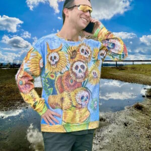 Person wearing a surreal sunflower‑and‑skull sweatshirt inspired by post‑impressionist florals, standing outdoors under a bright sky. Model wears XL.